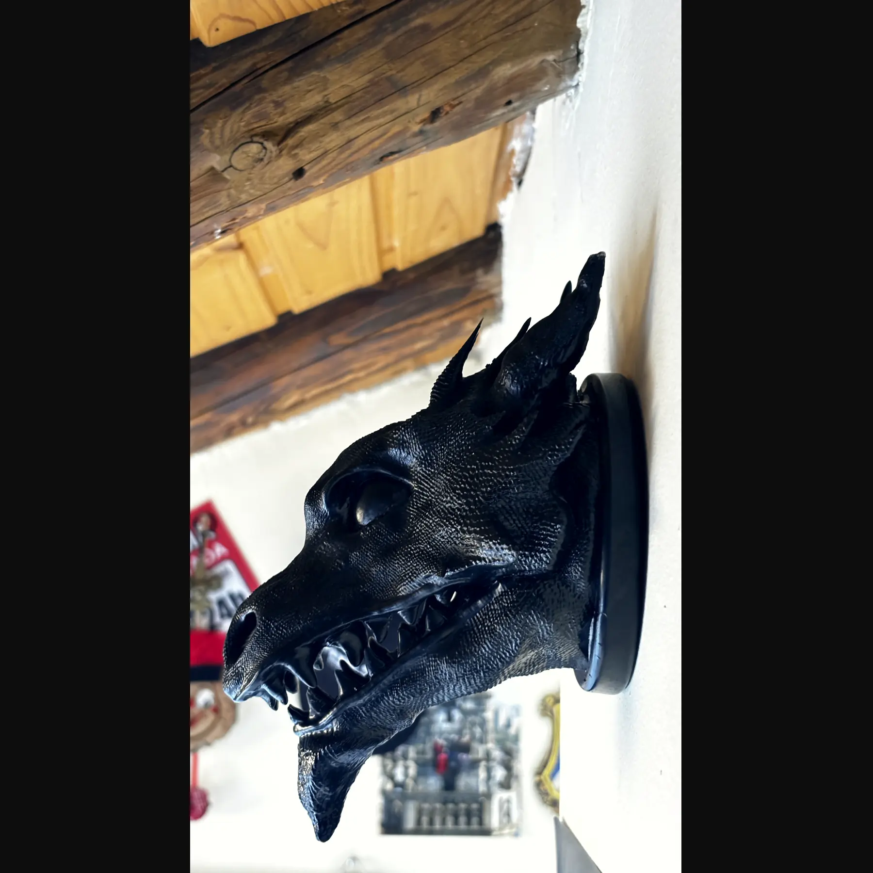The finished Drachenkopf held in an open hand against wood: a horned dragon head in dark resin
