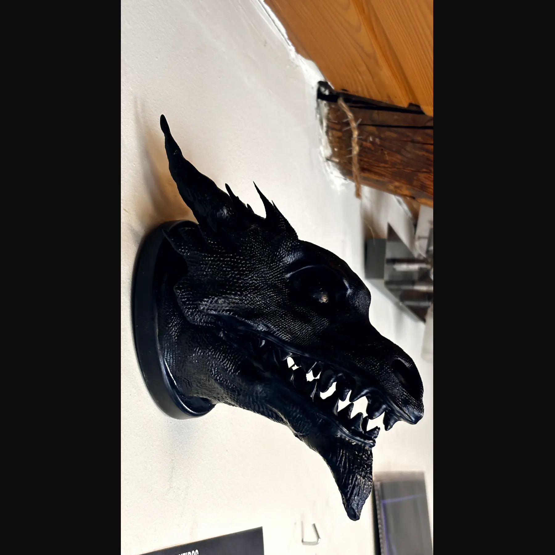 The finished Drachenkopf held in an open hand against wood: a horned dragon head in dark resin