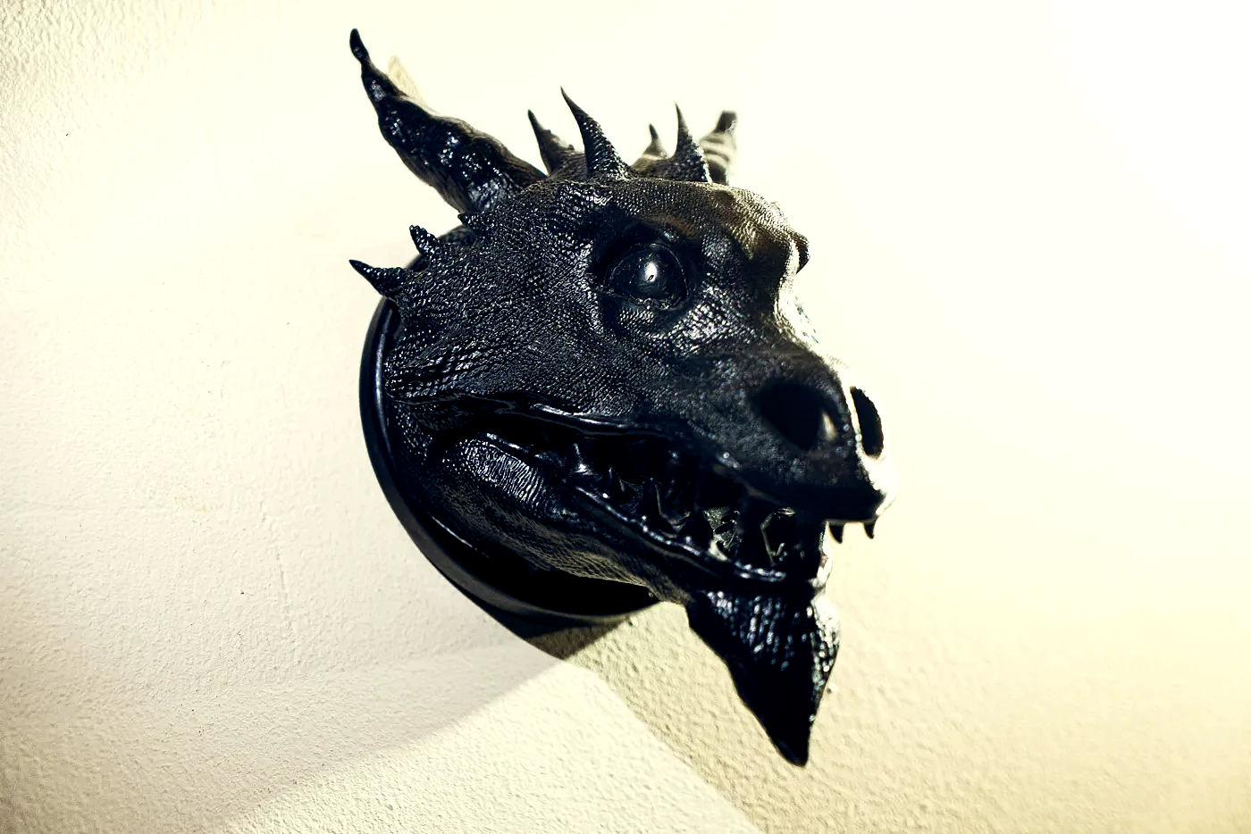 The finished Drachenkopf held in an open hand against wood: a horned dragon head in dark resin