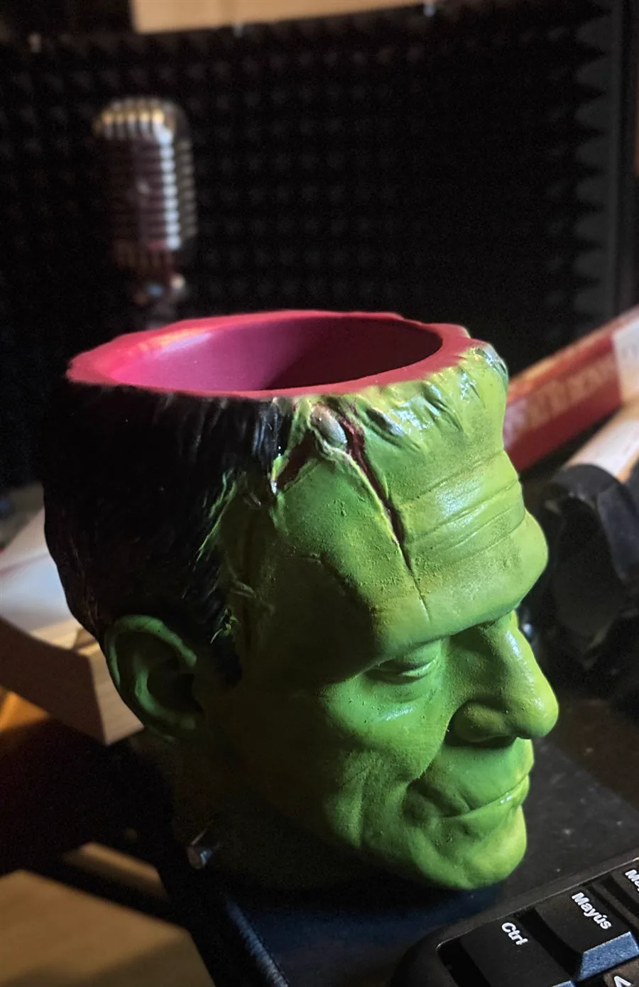 The Frankenstein cup rendered in 3D against black, seen face on, the stitches and bolts catching the light