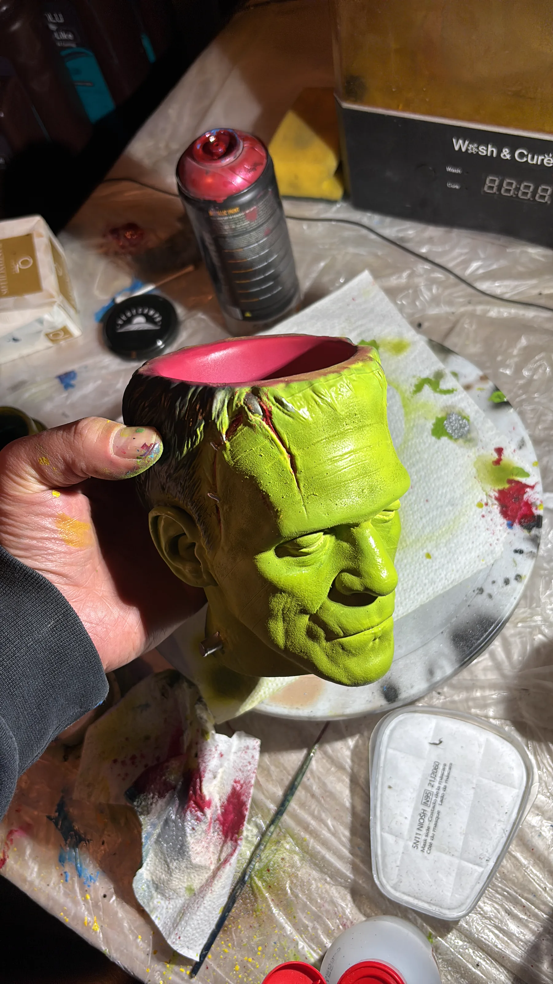 The Frankenstein cup rendered in 3D against black, seen face on, the stitches and bolts catching the light