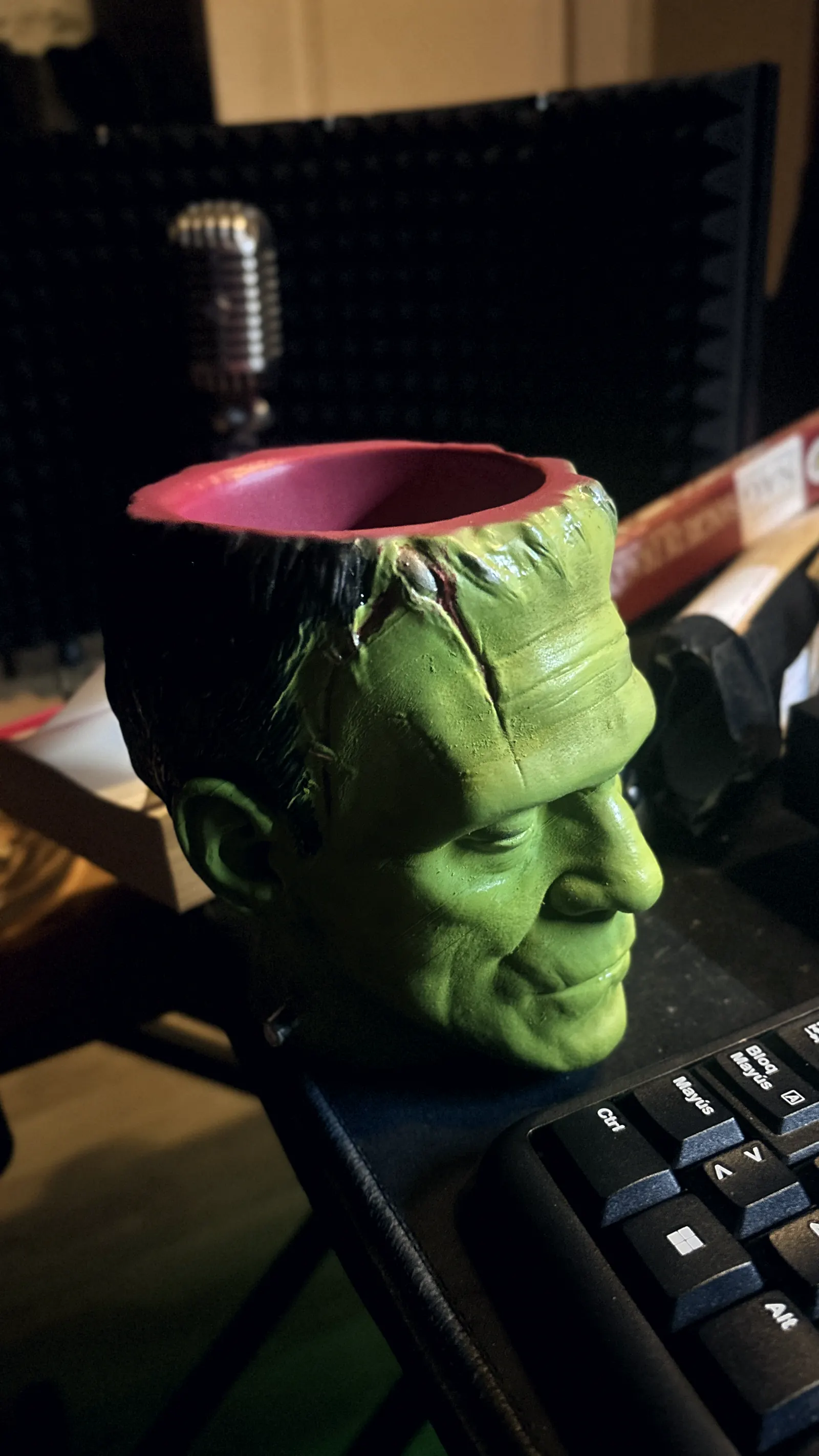 The Frankenstein cup rendered in 3D against black, seen face on, the stitches and bolts catching the light