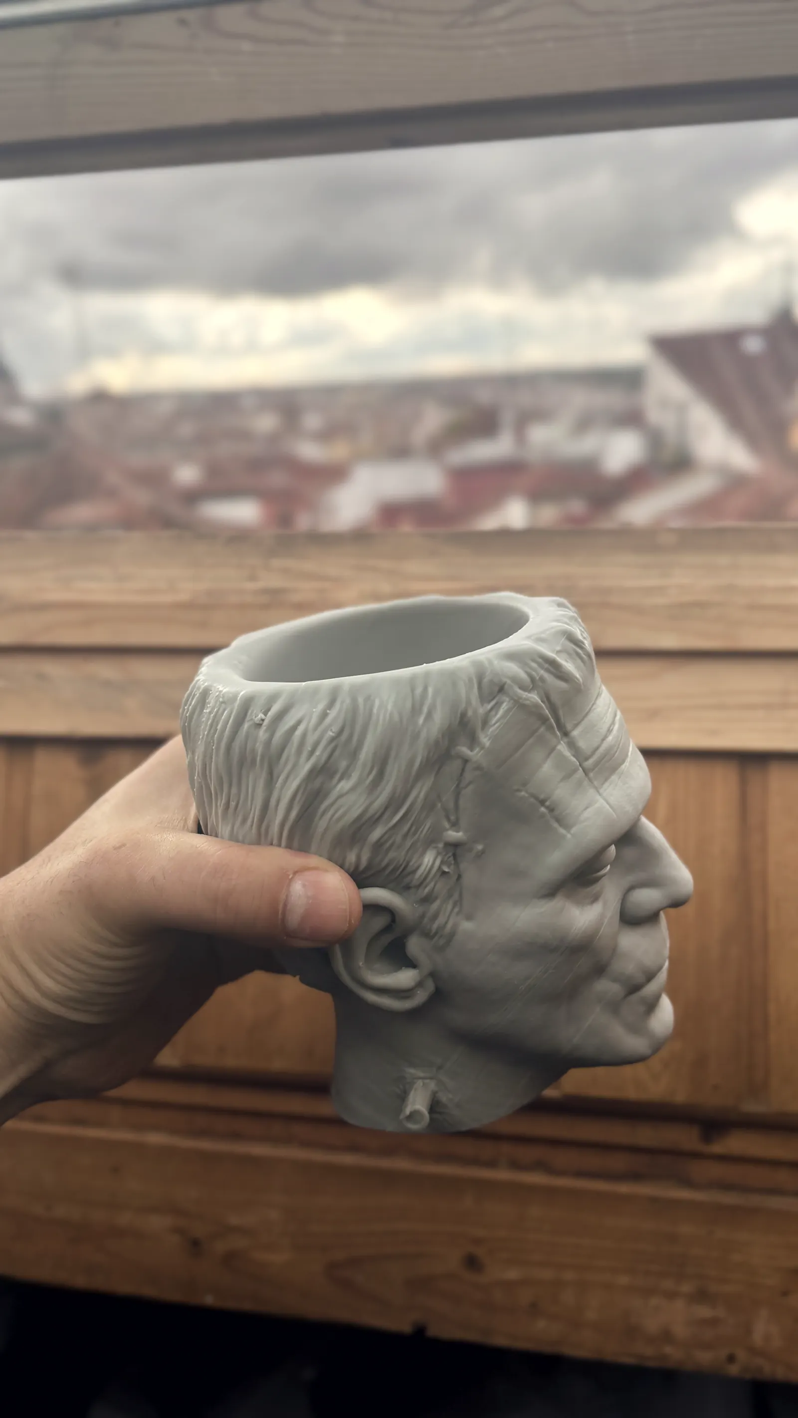 The Frankenstein cup rendered in 3D against black, seen face on, the stitches and bolts catching the light