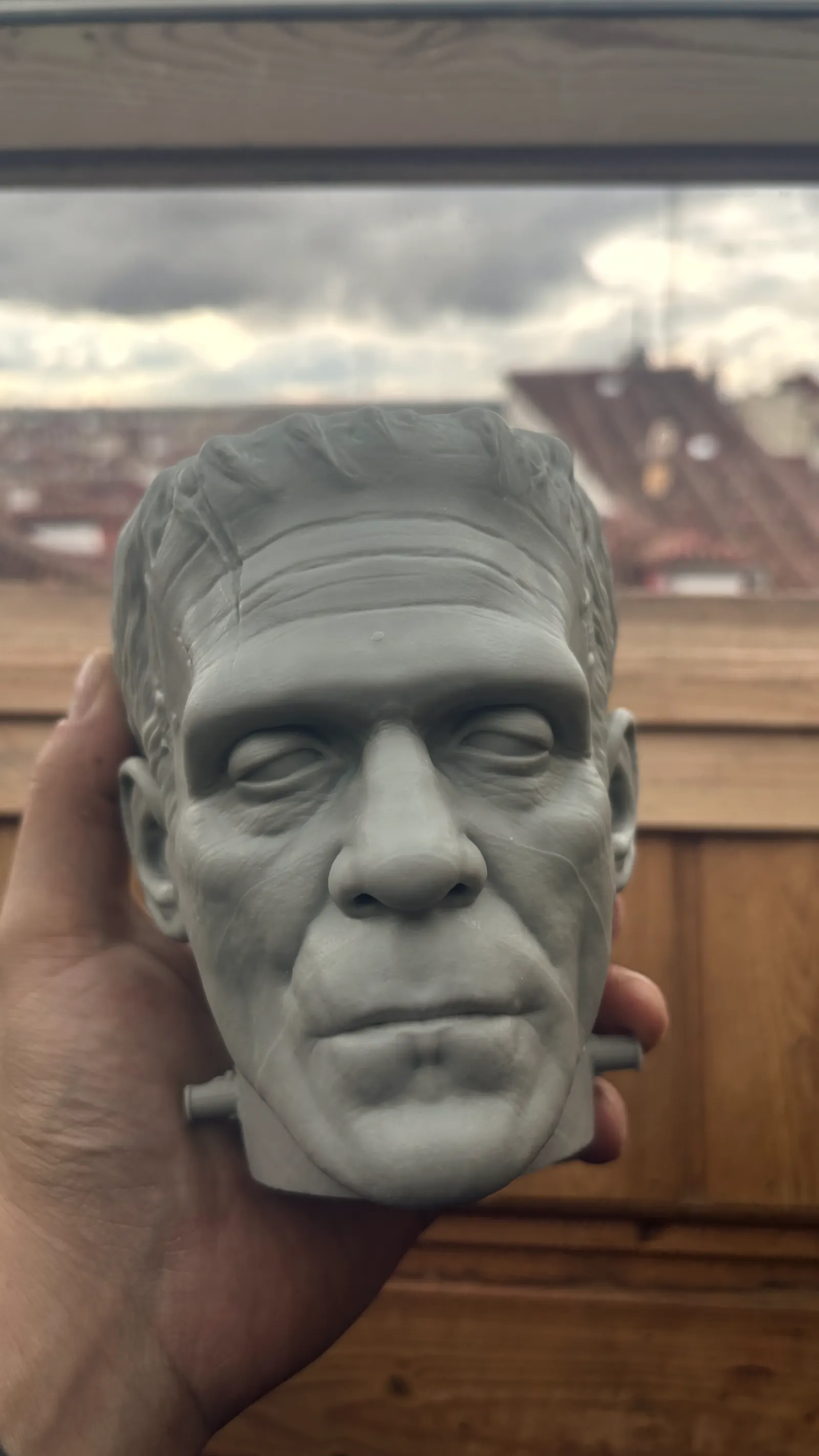 The Frankenstein cup rendered in 3D against black, seen face on, the stitches and bolts catching the light