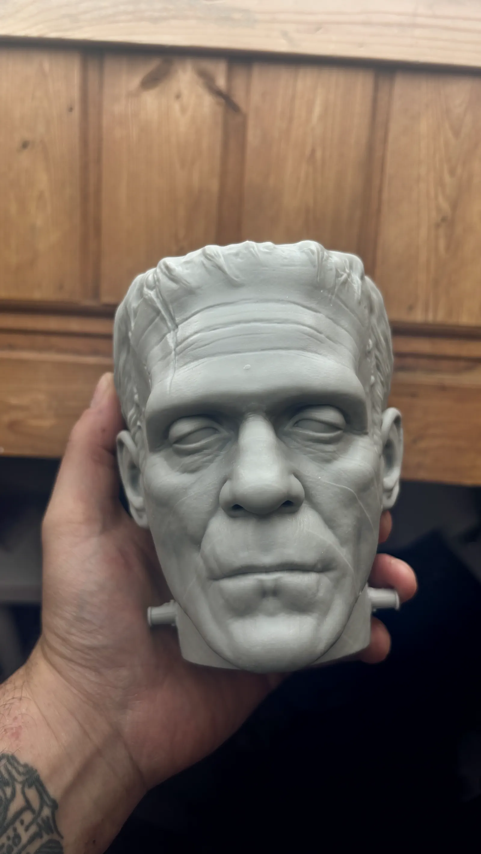 The Frankenstein cup rendered in 3D against black, seen face on, the stitches and bolts catching the light